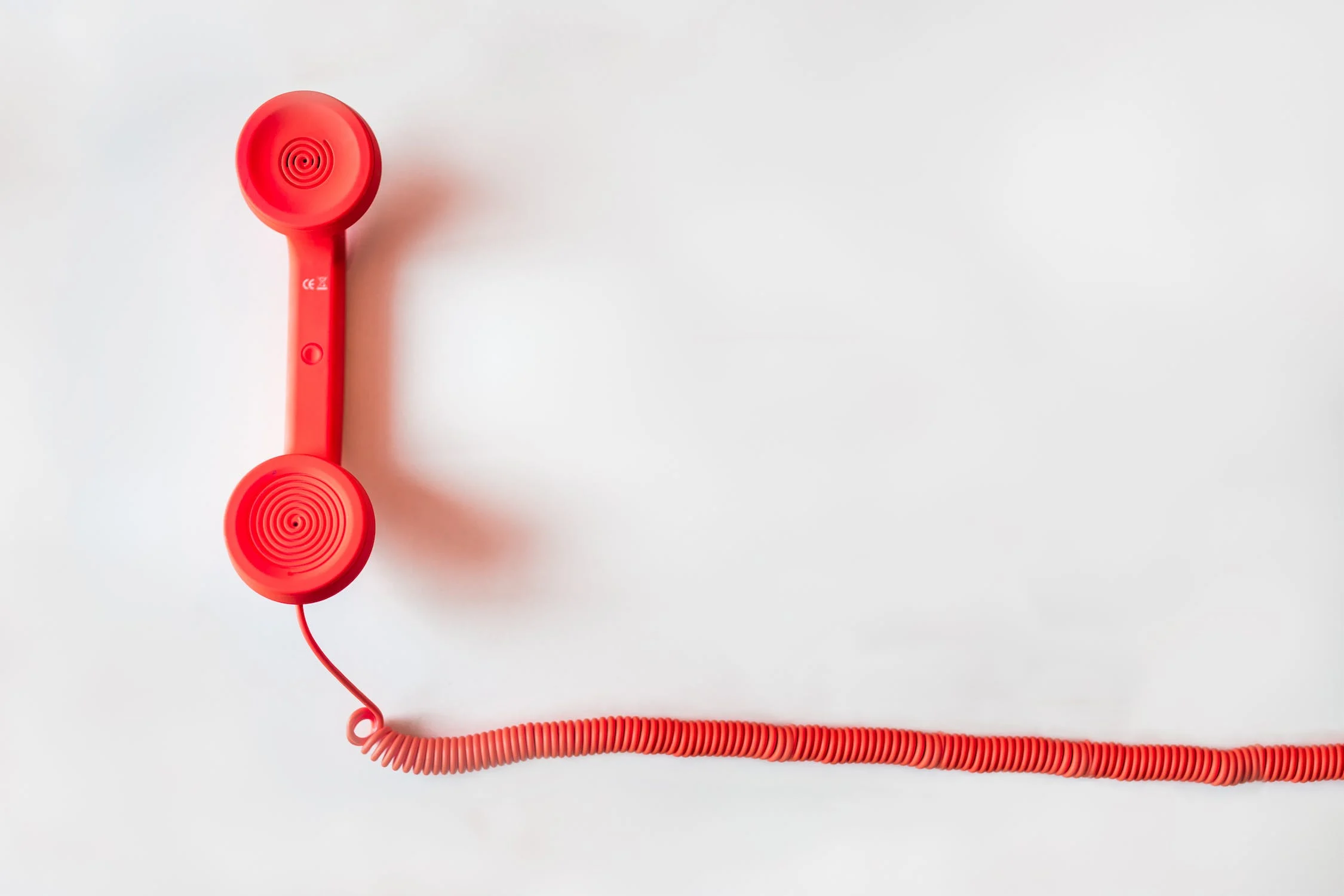a red phone handset and cord on a white background